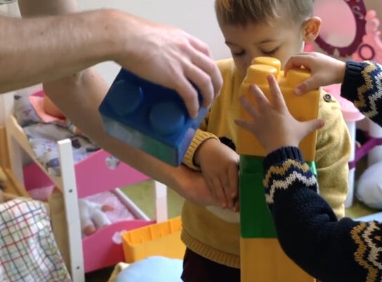 volwassen handen helpen kindjes blokkentoren bouwen