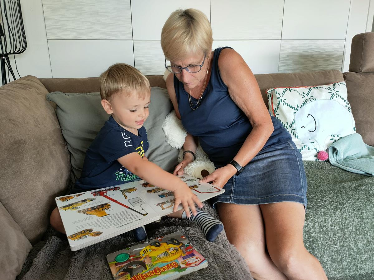 Dame leest boek met kindje in zetel