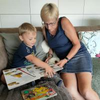 Dame leest boek met kindje in zetel